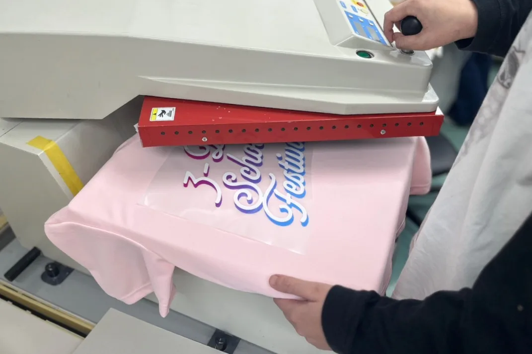 熱プレス機でフルカラープリントをTシャツに圧着する作業